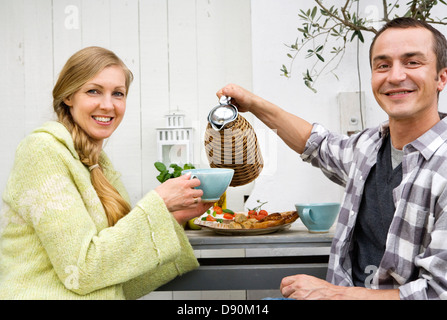 A middle aged couple having coffee in a greenhouse. Stock Photo