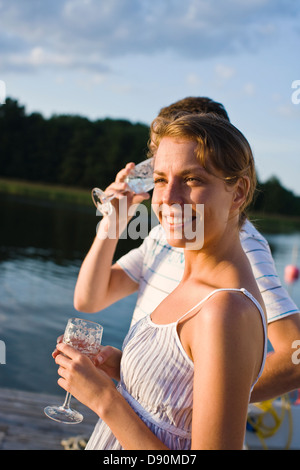 Couple standing by lake with glasses Stock Photo