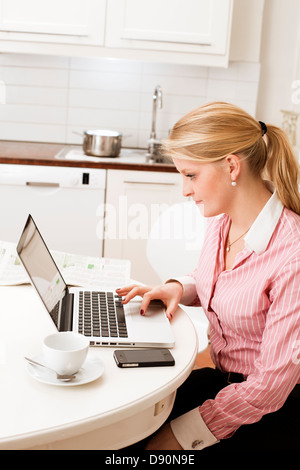 Young woman using laptop in kitchen Stock Photo