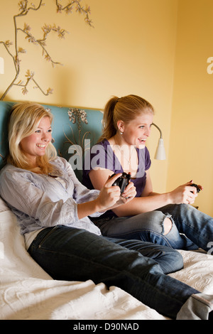 Two young women playing video game in bedroom Stock Photo