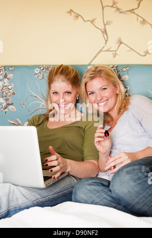 Two young women using laptop in bedroom Stock Photo