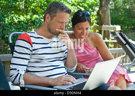 Couple using laptop in garden Stock Photo