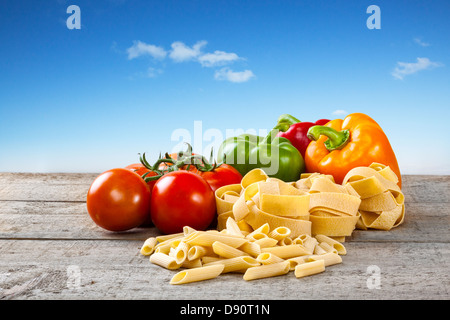 Pasta and Vegetables on Rustic Background - raw bronze die pasta and vegetables on a rustic... Stock Photo