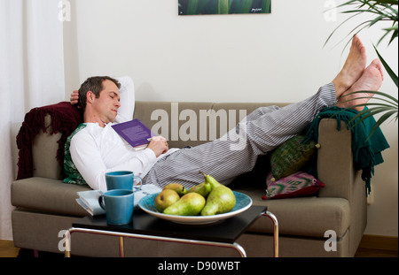 Mid adult man lying on sofa and sleeping Stock Photo