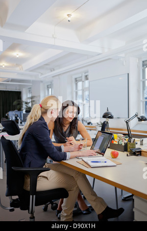 Two businesswomen using laptop in office Stock Photo