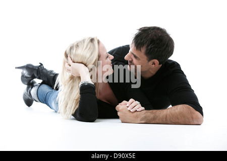 Studio shot of young couple lying on floor, embracing Stock Photo