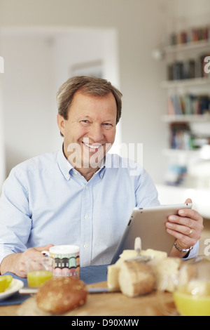 Portrait of mature man using digital tablet at table Stock Photo