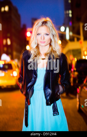 Young woman wearing leather jacket on street at night Stock Photo
