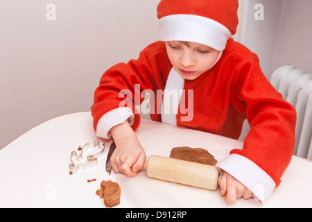 Boy wearing Santa hat preparing gingerbread Stock Photo