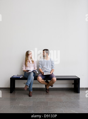 Young students sitting on bench Stock Photo