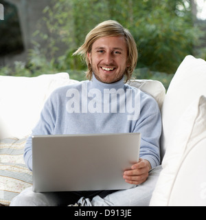 Portrait of a young smiling man using a laptop, Sweden. Stock Photo