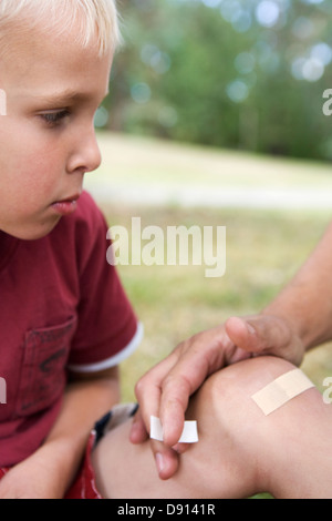 A father putting on a plaster on the knee of his son, Sweden. Stock Photo