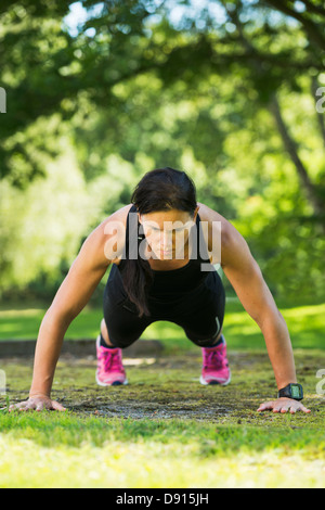 Woman doing push-ups in garden Stock Photo