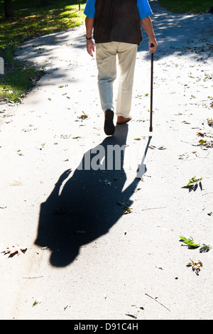 Shadow of an older man with a cane. Senior Disabled Stock Photo