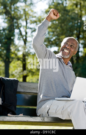 Senior man using a laptop in a park, Sweden. Stock Photo