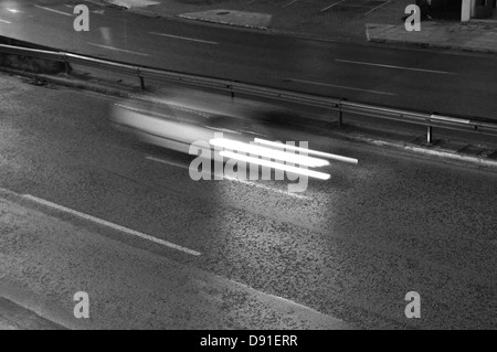 Speeding car on the motorway city traffic at night. Motion blur, black and white. Stock Photo