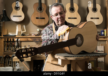 Guitar maker finishing acoustic guitar in workshop Stock Photo