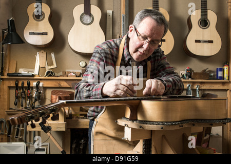 Guitar maker finishing acoustic guitar in workshop Stock Photo