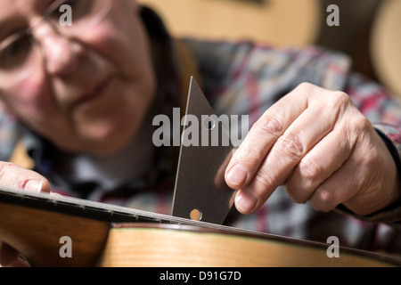 Close up of guitar maker finishing acoustic guitar in workshop Stock Photo