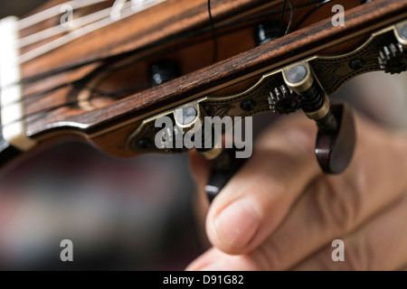 Close up of guitar maker tuning and testing acoustic guitar in workshop Stock Photo