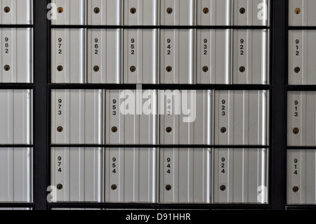 Image of steel gray United States Post Office mail boxes set into a wall. Stock Photo