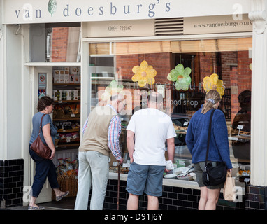 Shoppers browsing the window display of Van Doesburg's artisan food shop inthe High Street, Church Stretton, Shropshire Stock Photo