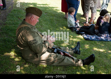 Hampshire, England, UK. 8th June 2013. A member of the Home Guard checks his mobile phone during War on the Line, a re-enactment of all things World War II celebrated on the Mid Hants Railway Watercress Line in Hampshire. Re-enactment societies dress in period civilian clothing or full military regalia as music, life on the home front and vehicles of the era are all on display, with a number of steam trains moving passengers to various stations along the line that participated in the event. Credit:  Patricia Phillips/Alamy Live News Stock Photo