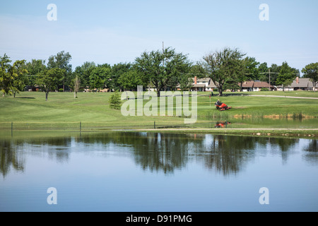 A groundskeeper mows grass near a green on Lake Hefner Golf Course in Oklahoma City, Oklahoma, . Stock Photo