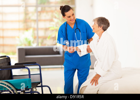 young female caregiver helping senior woman getting up Stock Photo