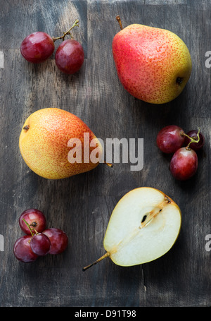 Fresh red pears and grapes on the dark wooden table, overhead Stock Photo