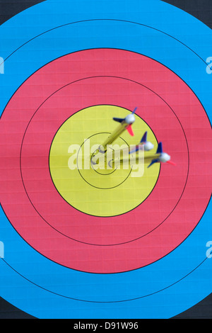 Three arrows embedded in the dead centre of an archery target Focus on target face Stock Photo