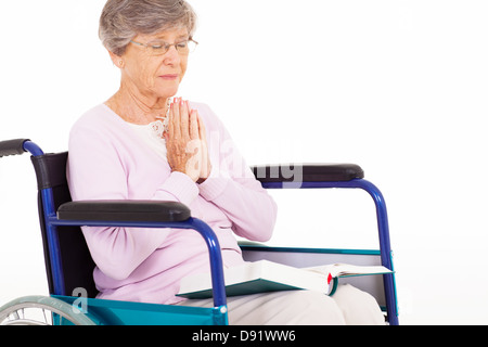 senior woman praying on wheelchair isolated on white Stock Photo