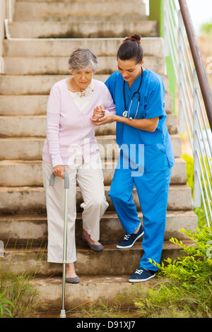 Doctor helping her patient to walk down the corridor for the first time ...