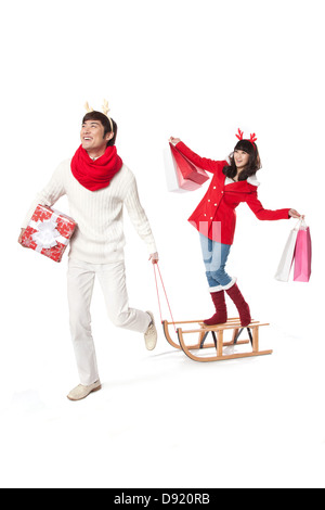 Young man pulling sled and young woman holding bags on it Stock Photo