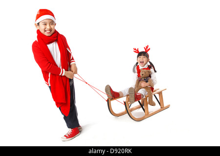 Boy pulling girl on sled Stock Photo