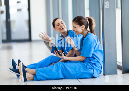 two female young nurses having fun with tablet computer during break Stock Photo