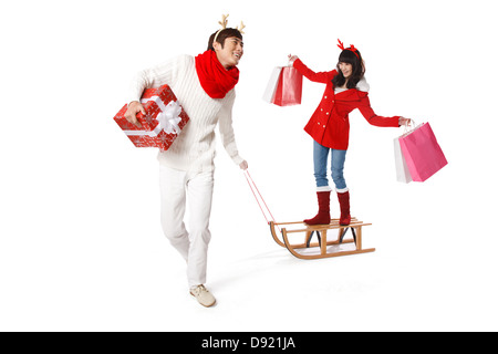 Young man pulling sled and young woman holding bags on it Stock Photo
