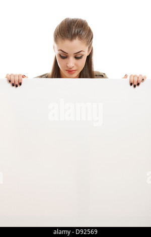 Portrait of beautiful happy business woman holding blank billboard and looking down on it. Isolated on white. Stock Photo