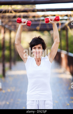active middle aged woman working out with dumbbells Stock Photo