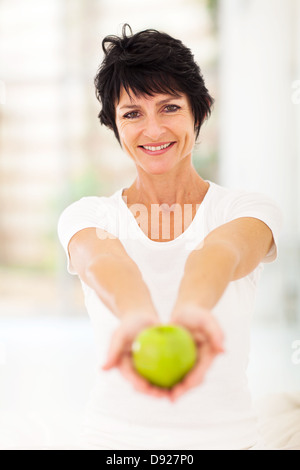 pretty mature woman holding a apple with both hands Stock Photo