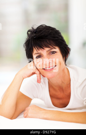 attractive middle aged woman lying on bed at home Stock Photo