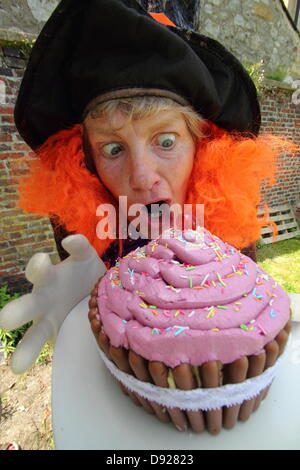 Bakewell, Derbyshire, UK. 9th June 2013. Bakewell Baking Festival. The Mad Hatter, Alison Benefield from Story Bag Theatre Company ditches tea for a giant cup-cake, Mad Hatter's Tea Party. Credit:  Deborah Vernon/Alamy Live News Stock Photo