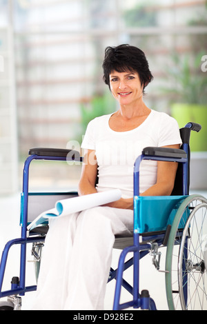 handicapped middle aged woman reading book on wheelchair Stock Photo