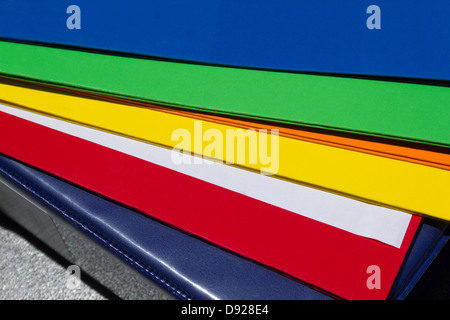 Close up image of vividly colored folders which are fanned out under a blue hard covered notebook Stock Photo