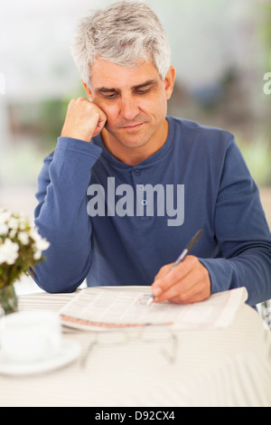 handsome middle aged man going through classified on newspaper Stock Photo