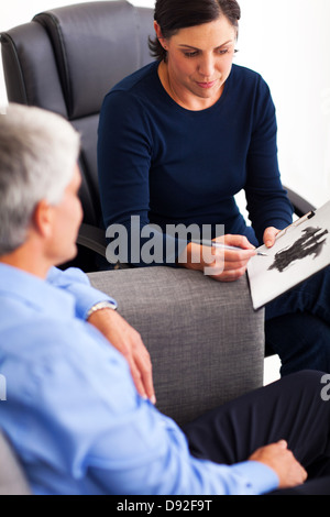 senior man doing Rorschach inkblot test with his therapist in office Stock Photo
