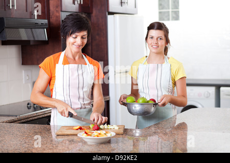 happy mother and daughter making fruit salad in kitchen Stock Photo