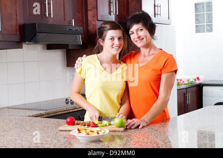 mother and teen daughter making fruit salad in kitchen Stock Photo
