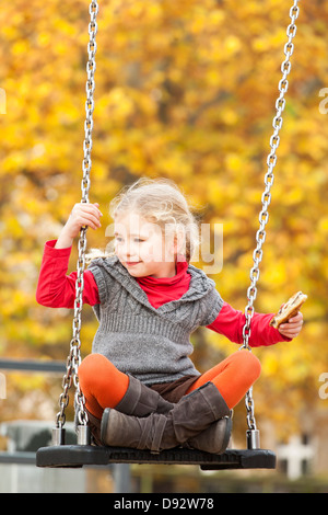 Girl on swing holding sandwich Stock Photo