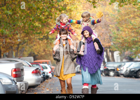 Two mothers with their daughters on their shoulders in Prenzlauer Berg, Berlin, Germany Stock Photo